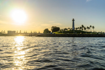 Scenic view of river by building against sky during sunset