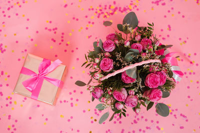 Bouquet of pink roses in a wicker basket and a gift box with a bow 