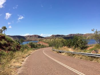 Road by mountains against clear blue sky