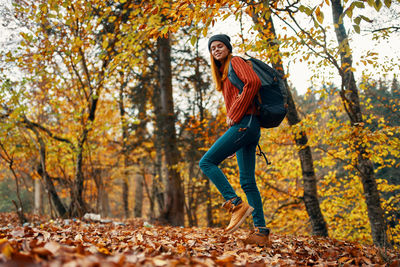 Portrait of young woman with autumn leaves in forest