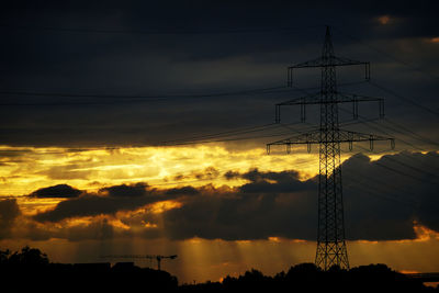 Low angle view of silhouette electricity pylon against sky during sunset