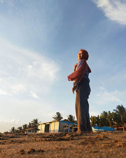 Low angle view of young woman standing on land against sky