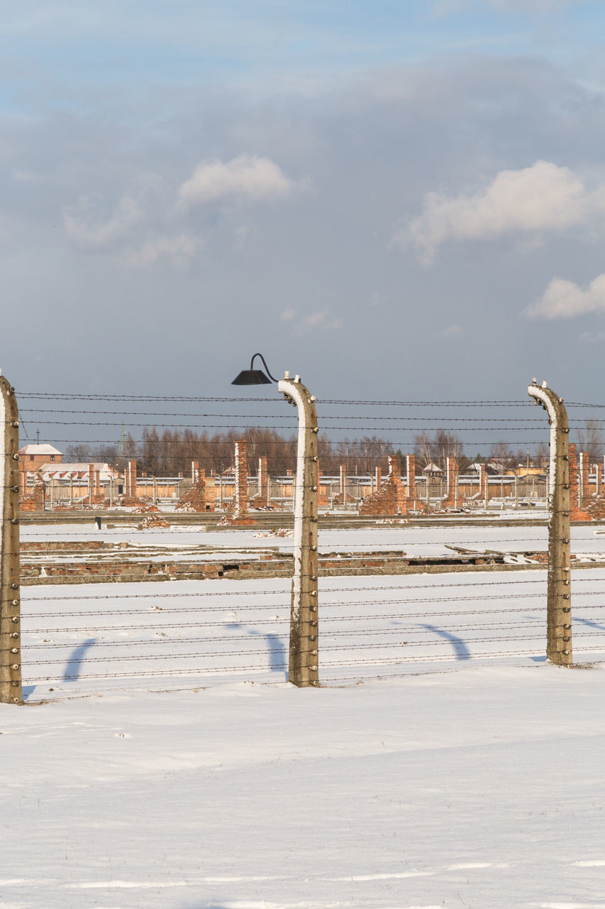 WOODEN POST ON SNOW COVERED LAND AGAINST SKY