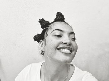 Portrait of smiling young woman against wall