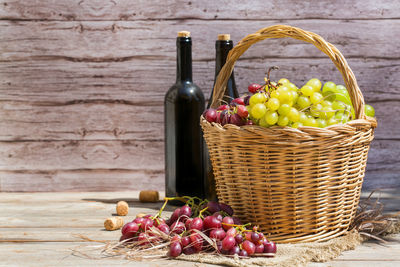 Various fruits in basket on wooden table