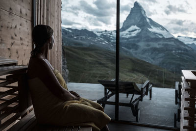 Woman looking thorough window at mountains