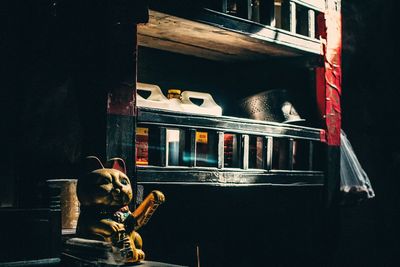 Maneki neko on table against shelf at home