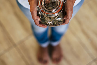 Low section of person holding coins in jar