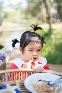 Cute girl eating food while sitting at park