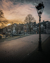 Street amidst buildings against sky during sunset