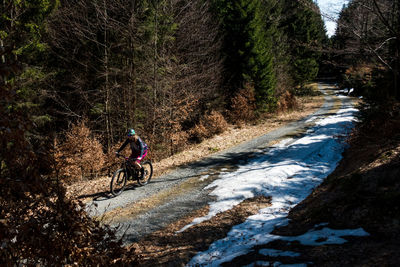 High angle view of young woman riding bicycle on road during winter