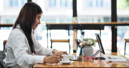 Young woman using smart phone at table