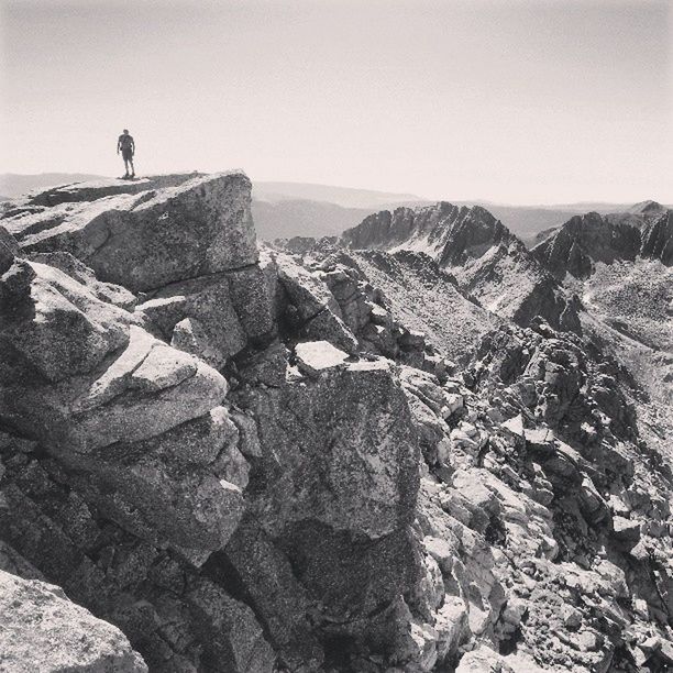 lifestyles, mountain, leisure activity, men, clear sky, tranquil scene, rock - object, tranquility, full length, scenics, standing, rear view, beauty in nature, nature, rock formation, hiking, copy space, sky