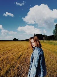 Portrait of woman standing on field against sky