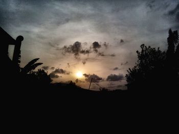 Silhouette of trees against cloudy sky