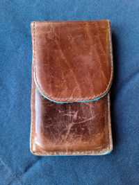 Brown handmade leather case for a smartphone on a blue background