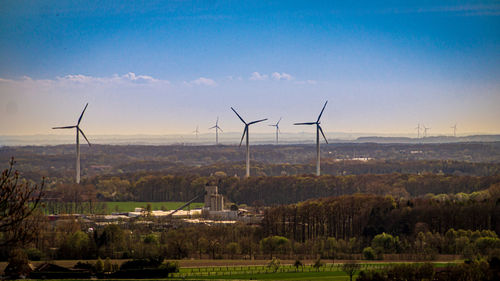 Wind turbines on field against sky