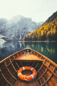 Wooden boat moored in lake by mountains