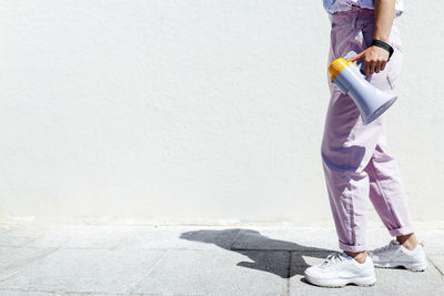 Woman holding megaphone while walking on footpath during sunny day