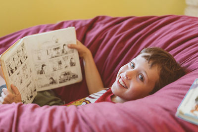 Portrait of boy with comic book lying on bean bag