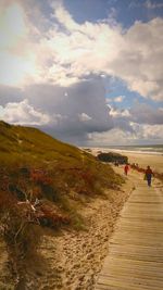 Rear view of people on beach against sky