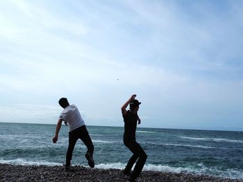 Men standing on beach against sky