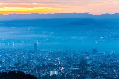 Aerial view of illuminated cityscape against sky during sunset