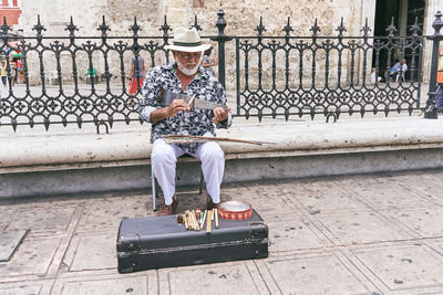 Full length of man sitting on street in city