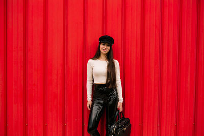 Portrait of woman standing against red wall