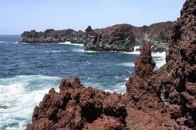 Scenic view of rocks on beach against sky