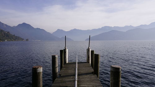 Wooden posts in sea against mountains