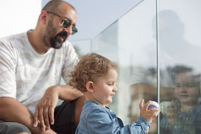 Father and daughter sitting on glass