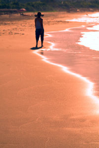 Full length of woman standing on beach during sunset