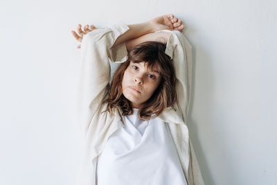 Portrait of young woman standing against wall