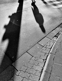 Shadow of person on footpath in city