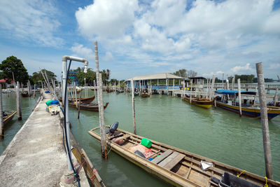 Boats moored at harbor against sky