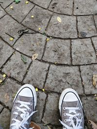 Low section of person in canvas shoes standing on footpath