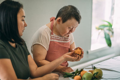 Lifestyle, education. elderly woman with down syndrome tries her cooked food in class with a teacher