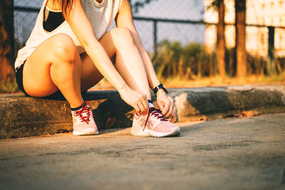 Low section of woman sitting on footpath