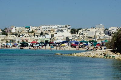 People at beach against clear blue sky