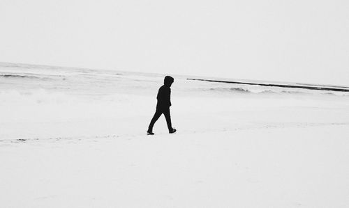 Full length of man standing on snow covered beach