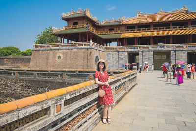 Portrait of woman standing by railing against historical building