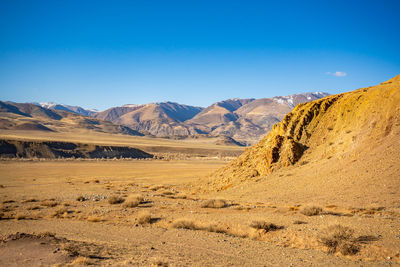 Scenic view of desert against clear blue sky