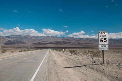 Road sign on landscape against sky