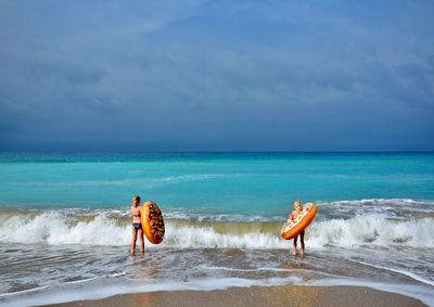 People on beach by sea against sky