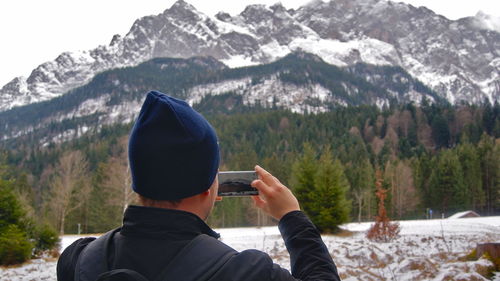 Rear view of person photographing in mountains