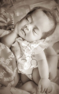Close-up of cute baby girl sleeping on bed at home