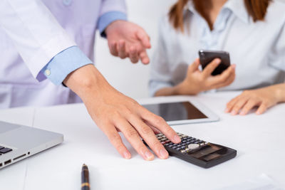 Midsection of woman using smart phone on table