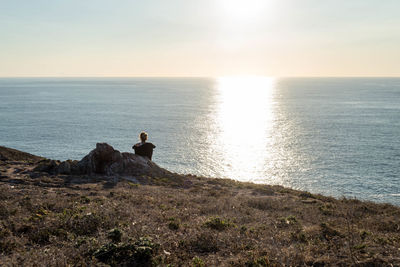 Silhouette man looking at sea against sky