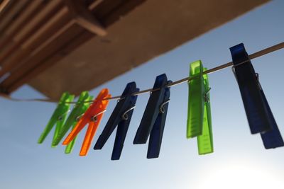 Low angle view of multi colored clothespins hanging on clothesline